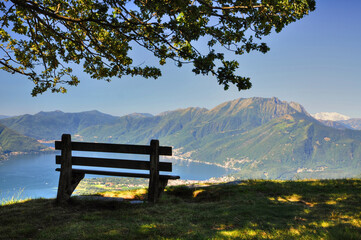Bench with Panoramic View over an Alpine Lake Maggiore with Mountain in a Sunny Day in Ticino, Switzerland.
