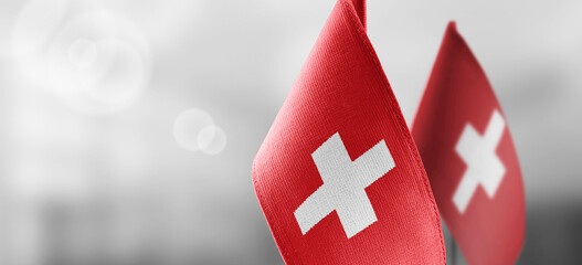 Small national flags of the Switzerland on a light blurry background