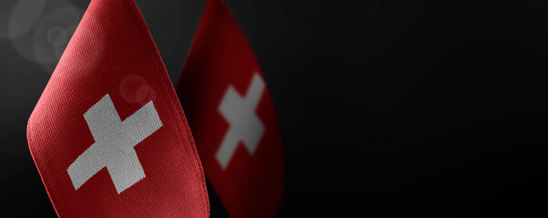 Small national flags of the Switzerland on a dark background