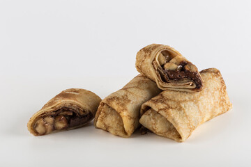 Several pancakes with banana filling with chocolate on a white background close-up with a copy space for the text, isolated.