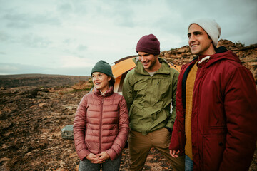 Fototapeta premium Smiling group of caucasian friends camping on top of mountain with tent