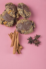 Chocolate nuts cookies on a pink background with cinnamon sticks