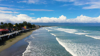 The city of Baler in the Philippines, known as the capital of surfing. Wide beach with big waves and surfers. Sabang Beach, Baler, Aurora, Philippines. Summer and travel vacation concept.