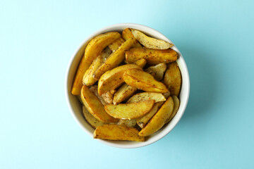 Bowl of potato wedges on blue background