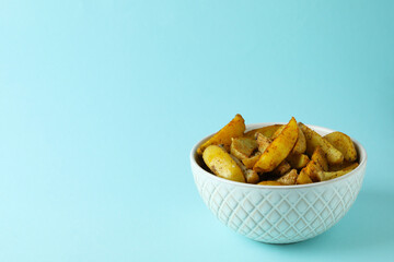 Bowl of potato wedges on blue background