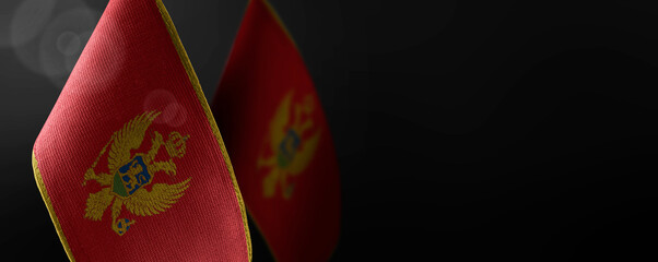 Small national flags of the Montenegro on a dark background