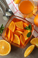 Obraz na płótnie Canvas Concept of dessert with bowl of orange jelly with orange slices on gray table