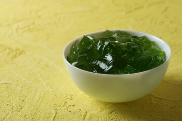 Bowl of kiwi jelly on yellow textured background