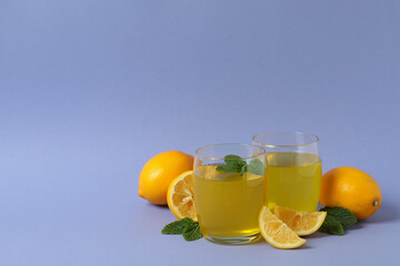 Glasses of lemon jelly, lemon slices and mint on violet background