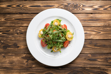 Salad with potatoes, salmon, arugula, tomatoes, lettuce and green onions