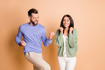 Photo of hooray nice couple hands fists wear sweater trousers yell isolated on beige color background