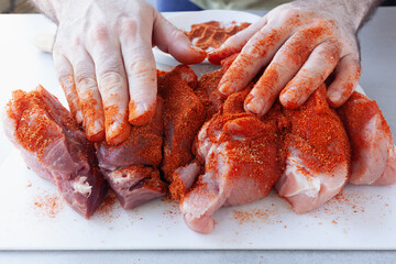 Male hands rubbing dry rub spices in pork tenderloin pieces, preparing it for grilling