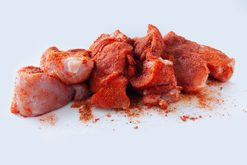 Pork tenderloin cut in pieces and covered with dry rub spices, ready for grill, on white background