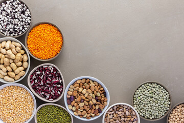 Different types of legumes in bowls, green and yellow peas, chickpeas and peanuts, colored beans and lentils, mung beans and beans, top view