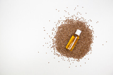 flaxseed oil in a transparent bottle with flax seeds on a white background top view