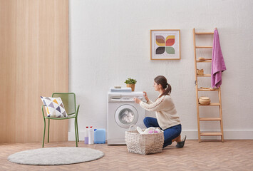 Laundry room washing machine and dirty clothes decorative modern style. Woman is taking or put...