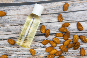 Fototapeta na wymiar almond oil in a transparent bottle with nuts on the background top view