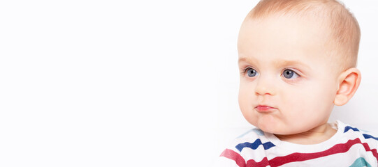 Portrait of funny caucasian baby boy with amazing blue eyes in striped t-shirt . Making faces. Banner format. Copy space. Surprised look on his face.