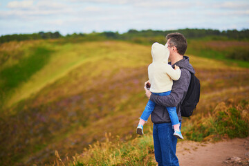 Man and toddler girl walking in heather meadows on Cape d'Erquy in Brittany, France