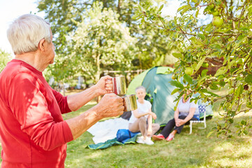 Senior serviert Kaffee in Bechern vor dem Zelt