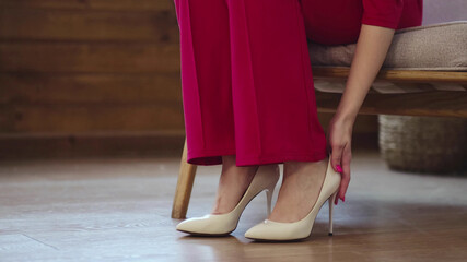 tired business woman takes off her shoes after a long day. swelling of feet after high heels, soft focus. Selective focus.