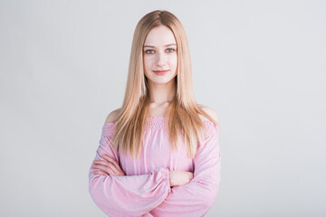 Portrait of a blonde girl who crossed her arms in the studio on a white background