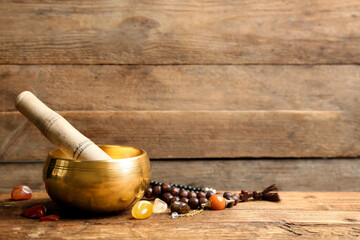 Composition with golden singing bowl on wooden table, space for text. Sound healing