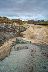Beautiful Icelandic landscape of colorful rainbow volcanic Landmannalaugar mountains, at famous Laugavegur hiking trail with dramatic snowy sky and hikers at distance in Iceland.