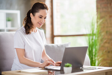 Photo of young happy cheerful focused concentrated businesswoman working in laptop remotely at home house
