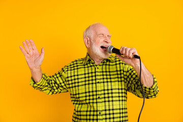 Photo of aged man excited enjoy sing song microphone karaoke event isolated over yellow color...