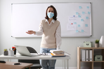 Teacher with protective mask conducting lesson in classroom. Reopening after Covid-19 quarantine