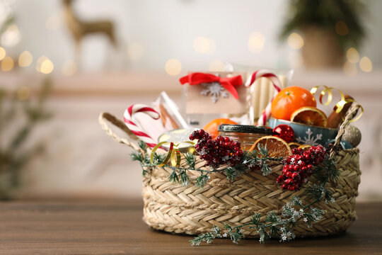 Wicker basket with Christmas gift set on wooden table. Space for text