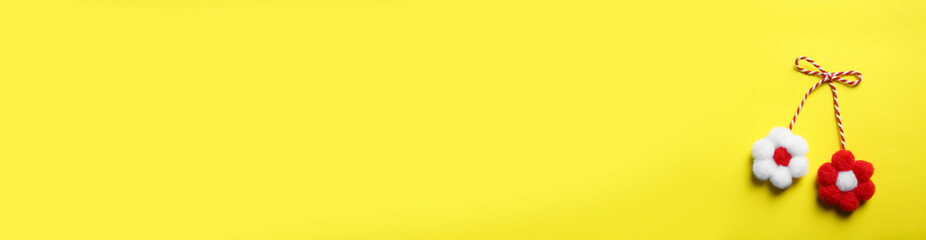 Traditional martisor shaped as flowers on yellow background, top view with space for text. Beginning of spring celebration