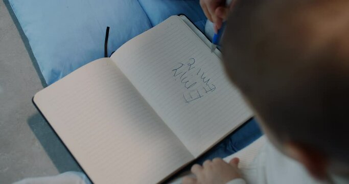 the mother helps the little child to write some words with a pen, slow motion.
