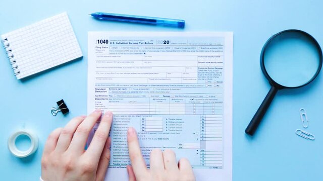 The person slides his finger along the lines of the 1040 tax form or reads a document. Taxation in the USA 