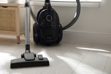 Modern vacuum cleaner on floor indoors, space for text