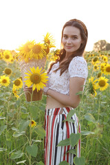 Girl walking in a sunflower field with a basket, rustic style photo, sunflower field at sunset