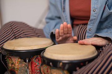 Fototapeta na wymiar Young faceless Caucasian woman playing small ethnic drums