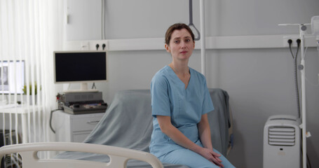 Upset crying female nurse sitting on empty hospital bed