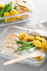 Lunch box containers with grilled chicken, rice and green beans with corn