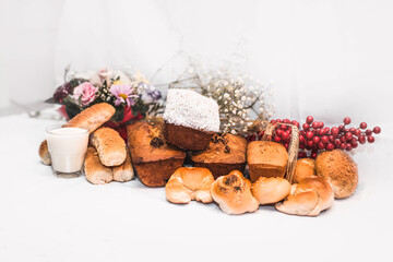 Buns of different types on a white tablecloth and a glass of milk