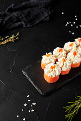 rolls with creamy sauce on a black wooden board on a black textured background