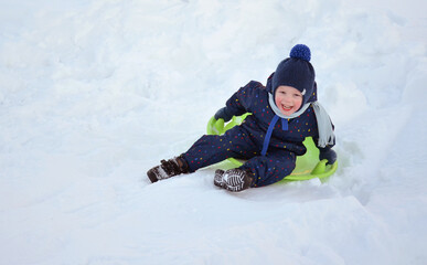 Fototapeta na wymiar A little boy is riding a slide. Winter.