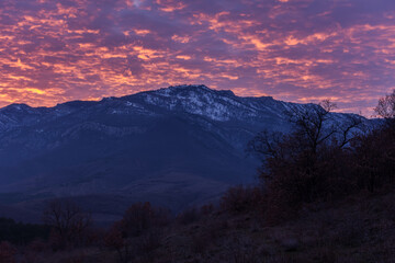 Naklejka na ściany i meble Sunset pink, red glow over the mountains. Atmospheric majestic sky landscape. A combination of orange and purple. Natural background at dusk, mountain tops, without people. The concept of tranquility
