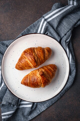 Croissants on plate on dark background. Top view 