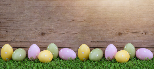 Easter background banner panorama greeting card - Many pastel painted dotted Easter eggs on fresh green meadow grasses and rustic wooden wood wall
