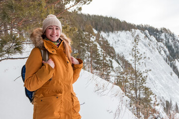 smiling woman in hiking clothes in the winter forest on the background of a beautiful view