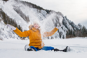 tourist woman traveler throws snow sitting in a snowdrift