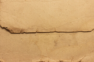 The texture of old stained, faded cardboard. Cardboard sheet with torn, frayed edges.