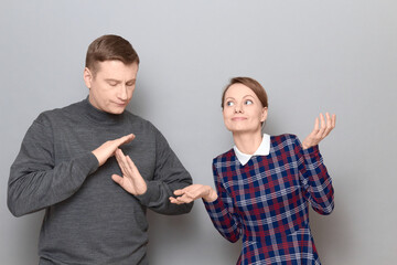 Woman is trying to explain something, man is showing stop gesture